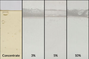 ZERUST Axxatec 77C rust inhibitor concentrate alongside samples diluted at 3%, 5%, and 10% concentrations, demonstrating its water-dilutable properties for optimal rust protection