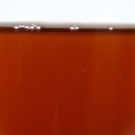 Ready-to-use ZERUST Axxatec 85-F dark amber liquid in a container, forming a clear, dry coating on metals, safe for painted surfaces and plastics.