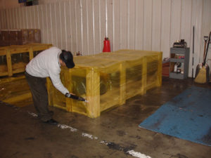 Crate being shrink-wrapped with VCI shrink film using heat gun
