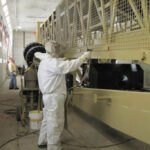 Employee applying ZERUST Axxanol Spray-G rust preventative grease on large equipment for corrosion protection.
