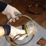 Employee applying ZERUST Axxanol Z-Maxx anti-corrosion grease to metal component for enhanced protection.