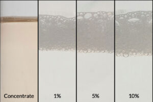 ZERUST AxxaWash KMS-310AL concentrate alongside dilutions at 1%, 5%, and 10% for effective aluminum and ferrous metal cleaning.