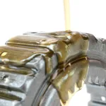 Non-staining rust preventive oil being poured onto a metal part to show its viscosity.