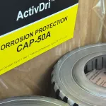 Moisture control capsule used with VCI packaging to protect metal components during export