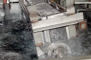 Low foam metal cleaner in automated parts washer system with controlled foam during operation