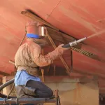 Wet blasting a ship hull during surface preparation for repainting
